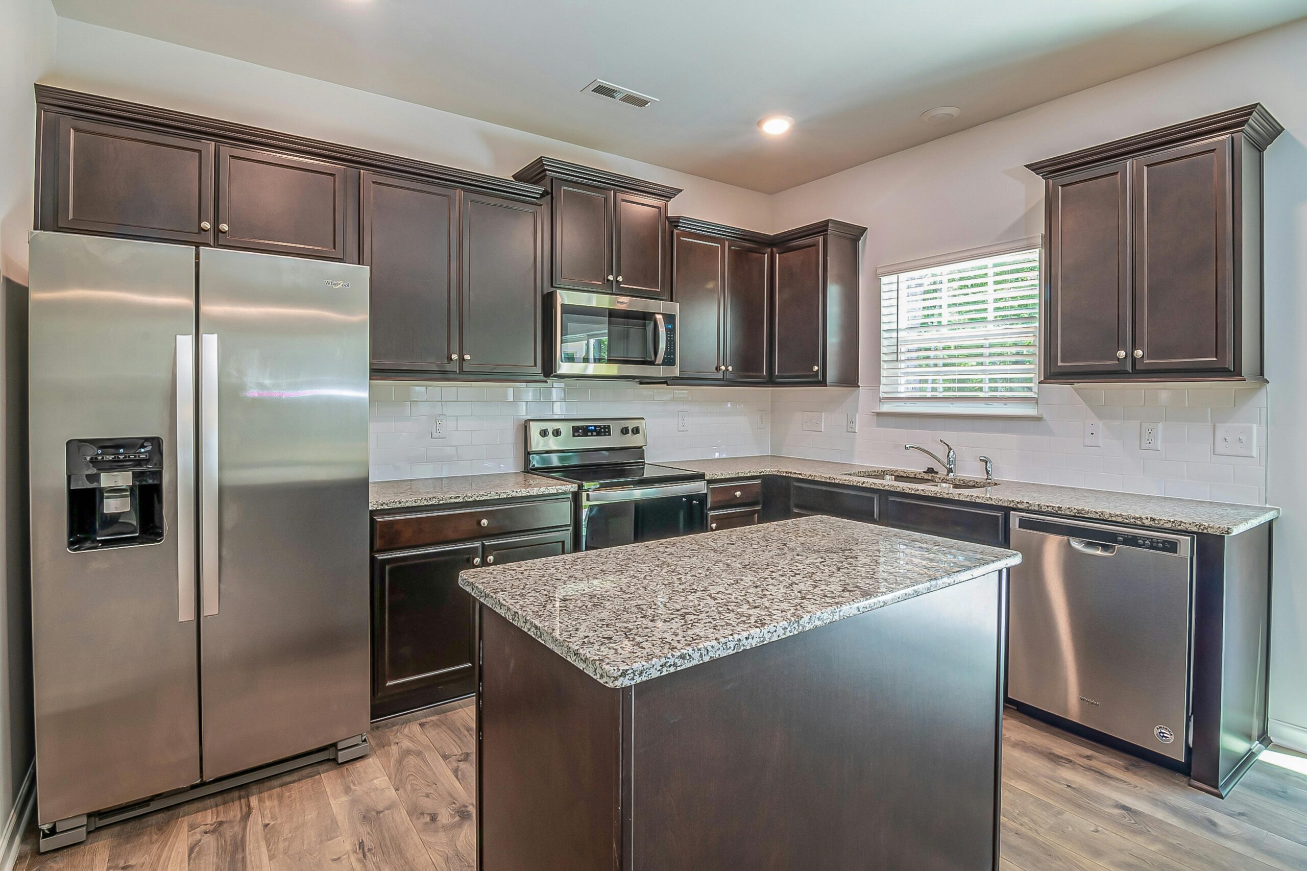 Elegant Kitchen with Dark Cabinets and Stainless Steel Appliances in Ada