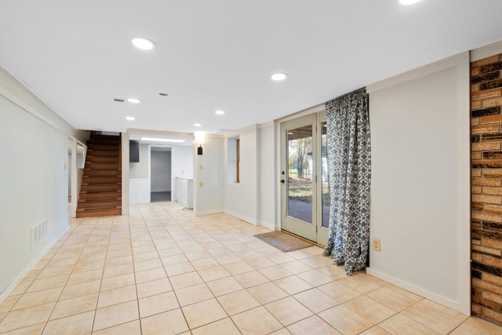 Open-concept basement with tile flooring, bright lighting, and outdoor access for added living space in Midland
