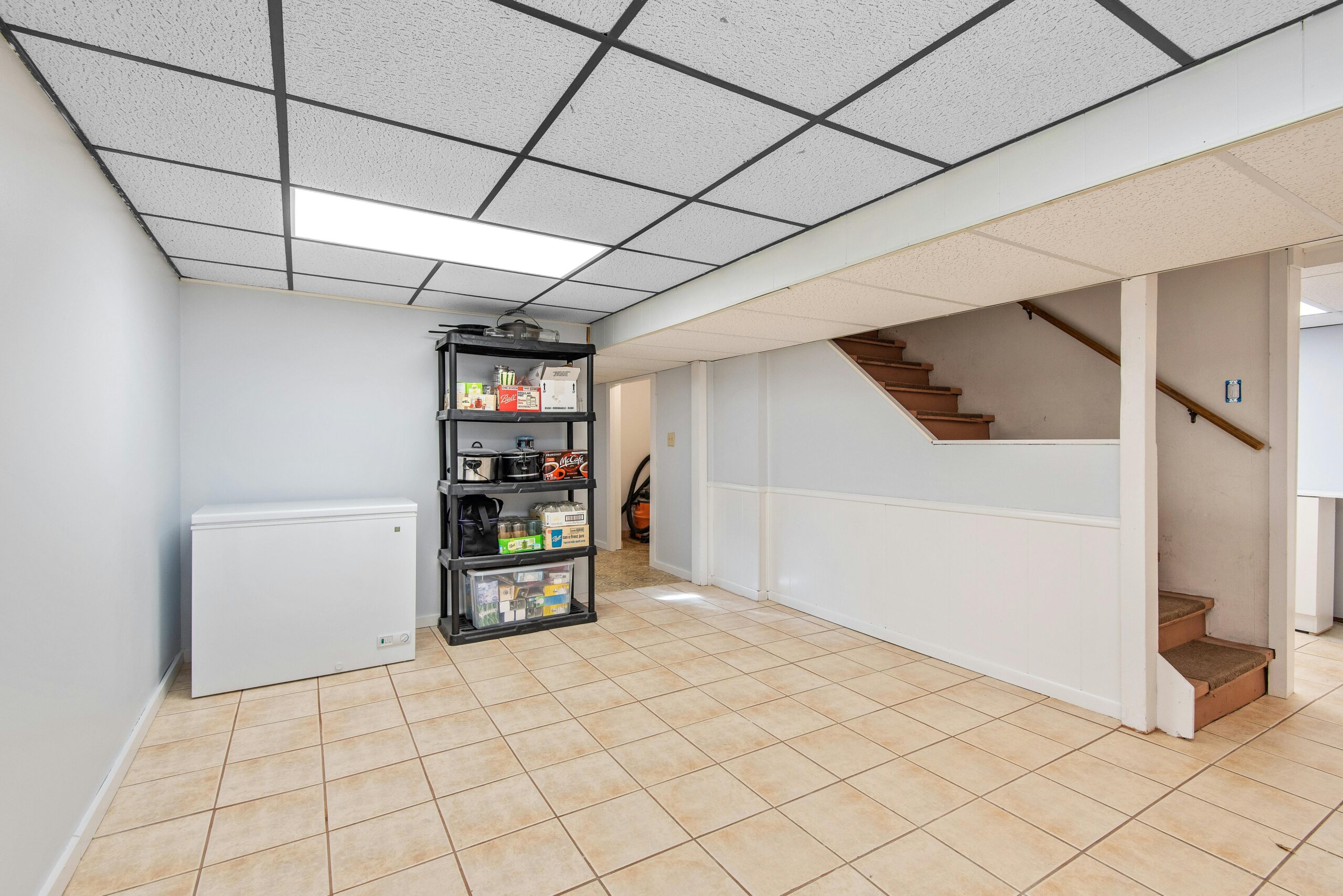 Open-concept basement with tile flooring, bright lighting, and outdoor access for added living space in Midland