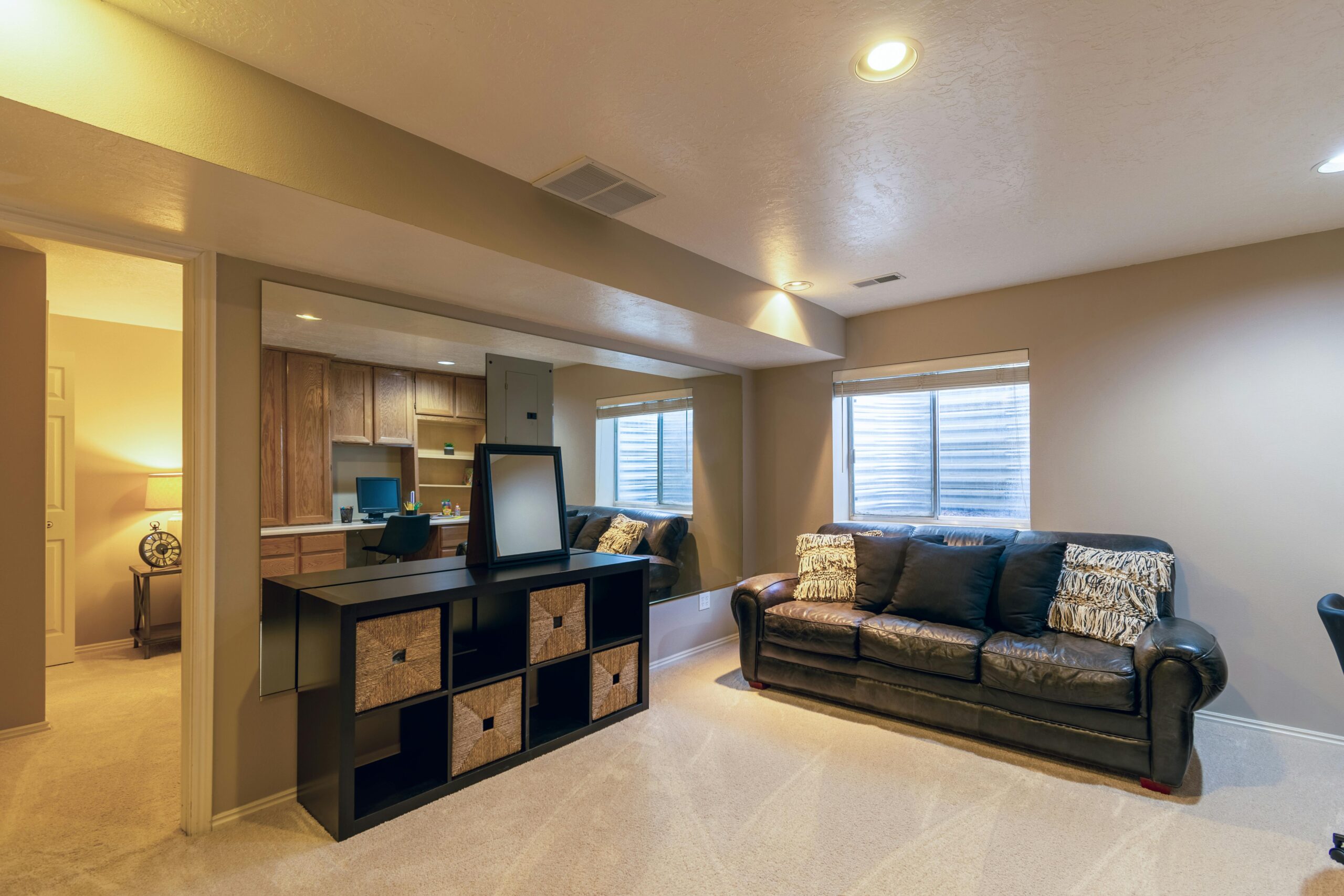 Comfortable basement remodel with soft lighting, carpet floors, and a built-in home office nook in Flint