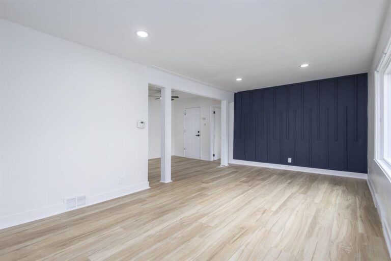 Modern finished basement with wood flooring and blue accent wall in Ferndale by Remodeling Warriors serving Macomb County and Oakland County
